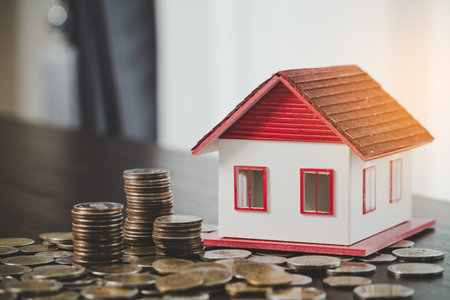 House model and money coins stacks on blur table background. Savings plans for home, loan, investment, mortgage, finance and banking about house concept.の写真素材