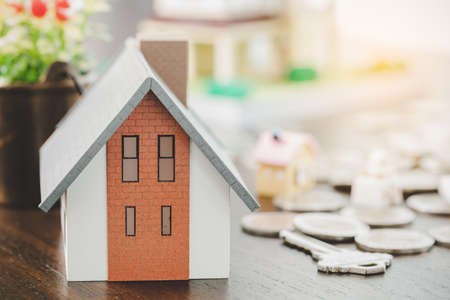 House model and money coins stacks on blur table background. Savings plans for home, loan, investment, mortgage, finance and banking about house concept.の写真素材