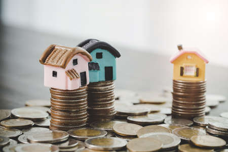 House model and money coins stacks on blur table background. Savings plans for home, loan, investment, mortgage, finance and banking about house concept.の写真素材