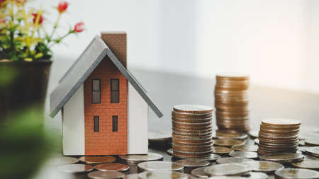 House model and money coins stacks on blur table background. Savings plans for home, loan, investment, mortgage, finance and banking about house concept.の写真素材