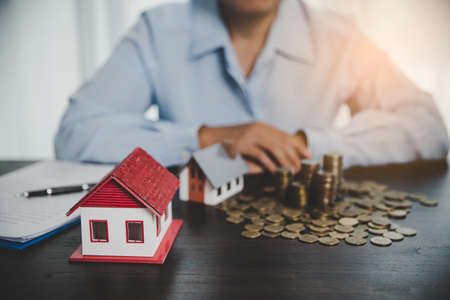 House model with stack coins, business hand is planning savings money of coins for buy home. concept for property ladder, mortgage with real estate investment and saving or investment for a houseの写真素材