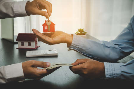 real estate agent holding house key to his client after signing contract, concept for business loan,...