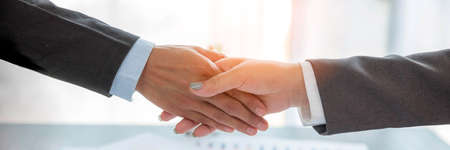 Professional businessman and businesswoman partners shaking hands together with business success deal and agreement. Hands business teamwork handshaking at office desk. Partnership banner copy spaceの写真素材