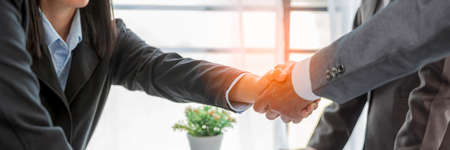 Professional businessman and businesswoman partners shaking hands together with business success deal and agreement. Hands business teamwork handshaking at office desk. Partnership banner copy spaceの写真素材