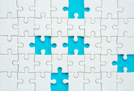 White part of jigsaw puzzle pieces on blue background. concepts of problem solving, business success, teamwork, Team playing jigsaw game incomplete, Texture photo with copy space for textの写真素材