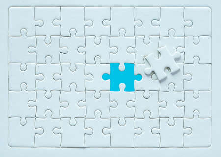 White part of jigsaw puzzle pieces on blue background. concepts of problem solving, business success, teamwork, Team playing jigsaw game incomplete, Texture photo with copy space for textの写真素材