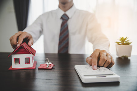 Real estate agents offer contracts to purchase or rent residential. Business person hands holding home model, small building red house. Mortgage property insurance moving home and real estate conceptの写真素材