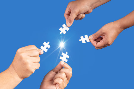 Hands holding jigsaw puzzles piece with clear blue background, success business, solution strategy, teamwork partnership conceptの写真素材