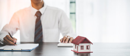 Real estate agents offer contracts to purchase or rent residential. Business person hands holding home model, small building red house. Mortgage property insurance moving home and real estate conceptの写真素材