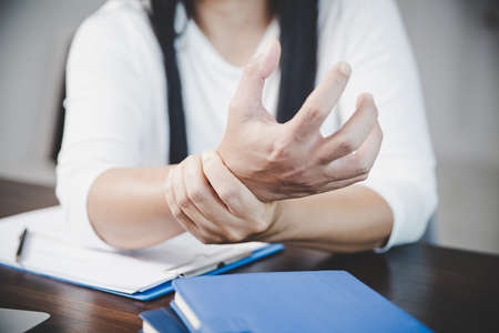 Arthritis person, finger woman ache from working in office. Concept office syndrome hand pain from occupational disease, woman having wrist pain from using laptop computer, wrist pain.の写真素材