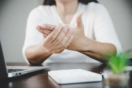 Arthritis person, finger woman ache from working in office. Concept office syndrome hand pain from occupational disease, woman having wrist pain from using laptop computer, wrist pain.の写真素材