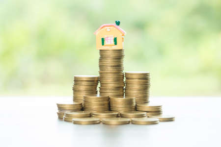 House and stack money coins with background to save for residential. Cash financial plan for loans or mortgages and investments with bank. Concept for house insurance business and real estate growthの写真素材