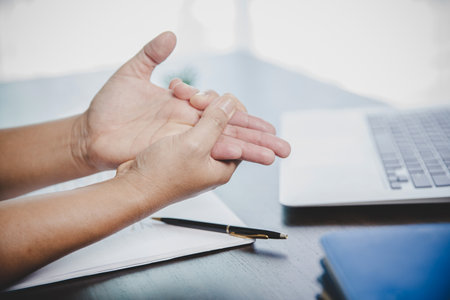 Arthritis person, finger woman ache from working in office. Concept office syndrome hand pain from occupational disease, woman having wrist pain from using laptop computer, wrist pain.の写真素材