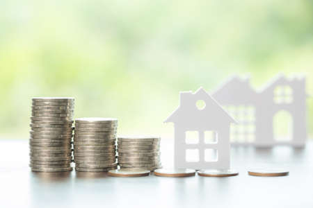 House and stack money coins with background to save for residential. Cash financial plan for loans or mortgages and investments with bank. Concept for house insurance business and real estate growthの写真素材