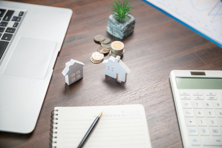 Model house and stack money coins on desk to save for residential. Cash financial plan for loans or mortgages and investments with bank. Concept for house insurance business and real estate growthの写真素材