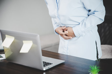 Young asian business woman person sitting at work and has stress pain in her stomach. Concept office syndrome abdomen pain from occupational disease, Female having belly pain and using laptop computerの写真素材