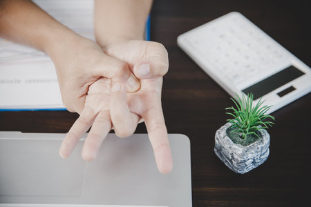 Arthritis person, finger woman ache from working in office. Concept office syndrome hand pain from occupational disease, woman having wrist pain from using laptop computer, wrist pain.の写真素材