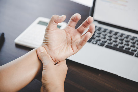 Arthritis person, finger woman ache from working in office. Concept office syndrome hand pain from occupational disease, woman having wrist pain from using laptop computer, wrist pain.の写真素材
