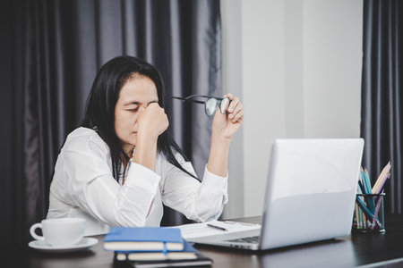 Stress business woman person from hard work, depression in office. Tired and anxious employee female with unhappy at problem job. young businesswoman sitting sad front of laptop computer on desk.の写真素材