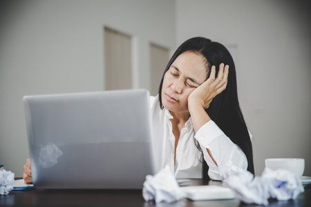 Stress business woman person from hard work, depression in office. Tired and anxious employee female with unhappy at problem job. young businesswoman sitting sad front of laptop computer on desk.の写真素材