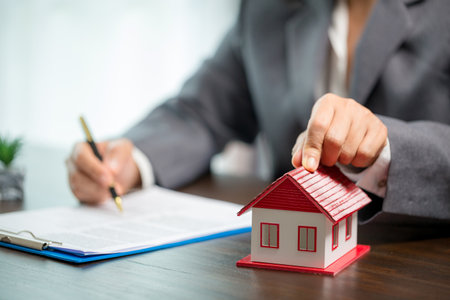 Woman home sales person is checking documents for house purchase contract before letting the customer sign contract on table is key with house model, real estate trading and insurance property conceptの写真素材