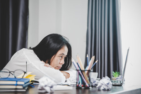 Stress business woman person from hard work, depression in office. Tired and anxious employee female with unhappy at problem job. young businesswoman sitting sad front of laptop computer on desk.の写真素材