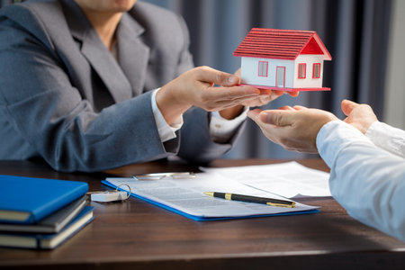 Woman home sales person is checking documents for house purchase contract before letting the customer sign contract on table is key with house model, real estate trading and insurance property conceptの写真素材