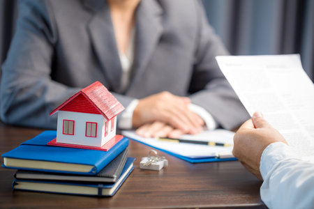 Woman home sales person is checking documents for house purchase contract before letting the customer sign contract on table is key with house model, real estate trading and insurance property conceptの写真素材