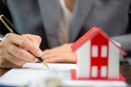 Woman home sales person is checking documents for house purchase contract before letting the customer sign contract on table is key with house model, real estate trading and insurance property conceptの写真素材