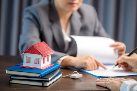 Woman home sales person is checking documents for house purchase contract before letting the customer sign contract on table is key with house model, real estate trading and insurance property conceptの写真素材