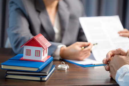 Woman home sales person is checking documents for house purchase contract before letting the customer sign contract on table is key with house model, real estate trading and insurance property conceptの写真素材