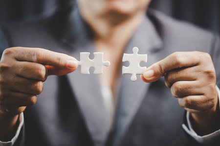 Business woman person hand holding puzzle piece idea for strategy and solution. Closeup part of two white jigsaw connect together. Concept of join cooperation success teamwork-problem corporate teamの写真素材