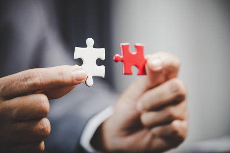 Business woman person hand holding puzzle piece idea for strategy and solution. Closeup part of two white jigsaw connect together. Concept of join cooperation success teamwork-problem corporate teamの写真素材