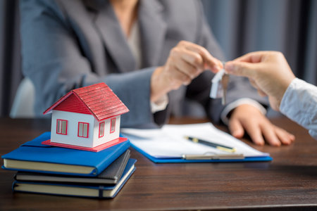 Woman home sales person is checking documents for house purchase contract before letting the customer sign contract on table is key with house model, real estate trading and insurance property conceptの写真素材