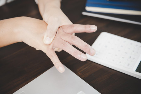 Arthritis person, finger woman ache from working in office. Concept office syndrome hand pain from occupational disease, woman having wrist pain from using laptop computer, wrist pain.の写真素材