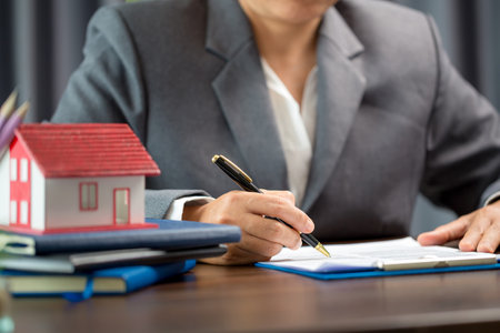Woman home sales person is checking documents for house purchase contract before letting the customer sign contract on table is key with house model, real estate trading and insurance property conceptの写真素材