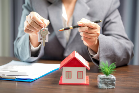 Woman home sales person is checking documents for house purchase contract before letting the customer sign contract on table is key with house model, real estate trading and insurance property conceptの写真素材