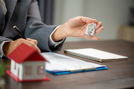 Woman home sales person is checking documents for house purchase contract before letting the customer sign contract on table is key with house model, real estate trading and insurance property conceptの写真素材