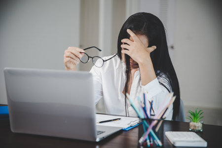 Stress business woman person from hard work, depression in office. Tired and anxious employee female with unhappy at problem job. young businesswoman sitting sad front of laptop computer on desk.の写真素材