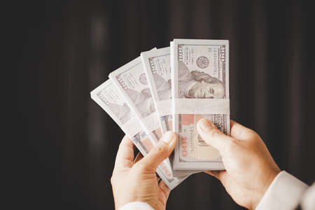 Banknote of 100 dollar bills in hands of rich woman person. Success business female holding cash money for investment. concept of saving finance, exchange bank, american currency, salary paymentの写真素材