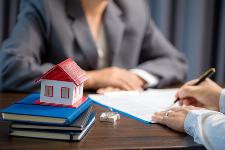 Woman home sales person is checking documents for house purchase contract before letting the customer sign contract on table is key with house model, real estate trading and insurance property conceptの写真素材