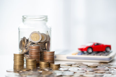Car toy vehicle with stack coin money on background. Planning to manage transportation finance costs. Concept of car insurance business, saving buy - sale with tax and loan for new car.の写真素材