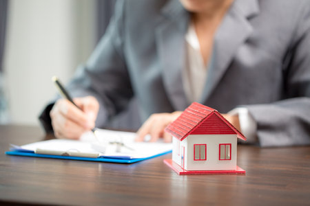 Woman home sales person is checking documents for house purchase contract before letting the customer sign contract on table is key with house model, real estate trading and insurance property conceptの写真素材