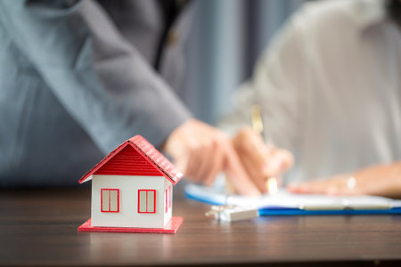 Woman home sales person is checking documents for house purchase contract before letting the customer sign contract on table is key with house model, real estate trading and insurance property conceptの写真素材