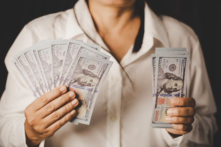 Banknote of 100 dollar bills in hands of rich woman person. Success business female holding cash money for investment. concept of saving finance, exchange bank, american currency, salary paymentの写真素材