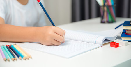 Boy person sitting study indoor at home, Male kid student online learning and doing homework on desk, young child reading and writing a book on table. concept of education, technology cyberspaceの写真素材