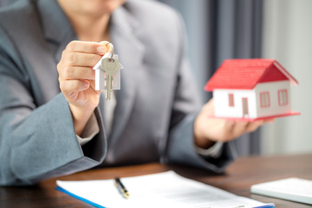 Woman home sales person is checking documents for house purchase contract before letting the customer sign contract on table is key with house model, real estate trading and insurance property conceptの写真素材