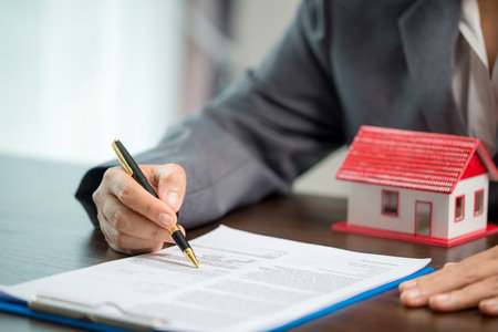 Woman home sales person is checking documents for house purchase contract before letting the customer sign contract on table is key with house model, real estate trading and insurance property conceptの写真素材