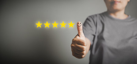 Hand with thumb up positive emotion smiley face icon and 5 star with copy space. Emotional smiley faces showing excellent satisfaction. rating very impressed. Customer service and satisfaction conceptの写真素材