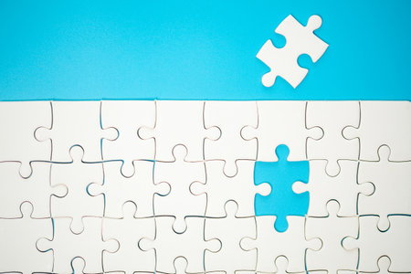 White part of jigsaw puzzle pieces on blue background. concepts of problem solving, business success, teamwork, Team playing jigsaw game incomplete, Texture photo with copy space for textの写真素材